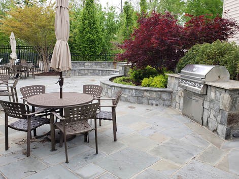 A concrete patio complete with BBQ and chairs and tables